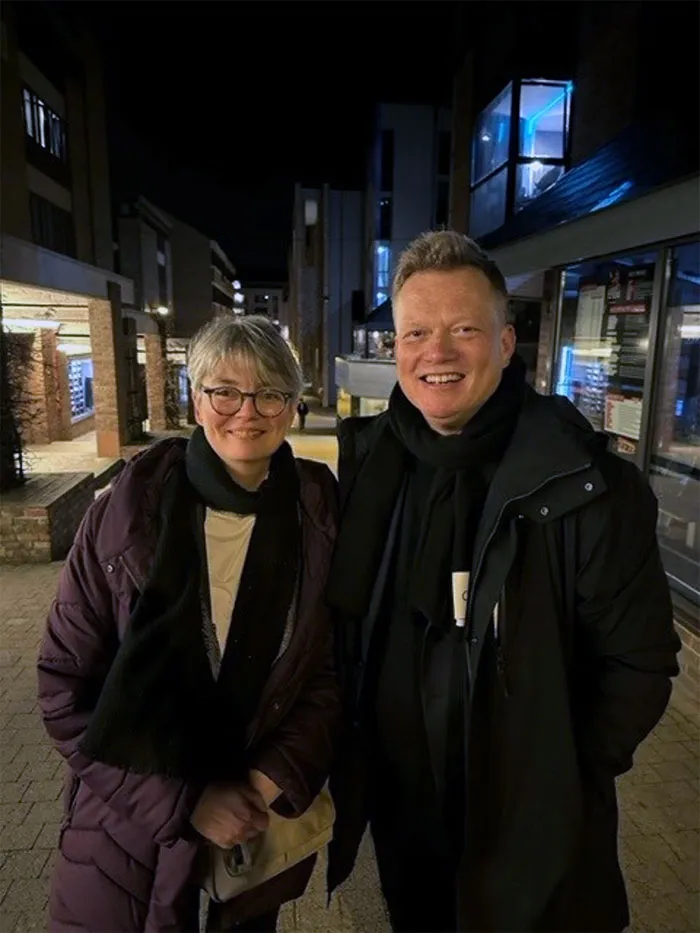 Two people facing the camera and smiling