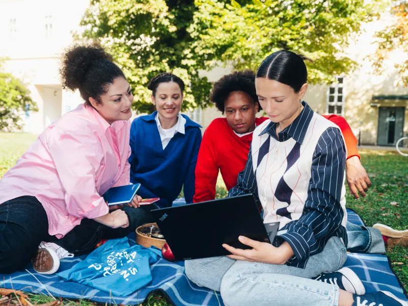 Circle U. Group of Students sitting in a park and looking at a laptop