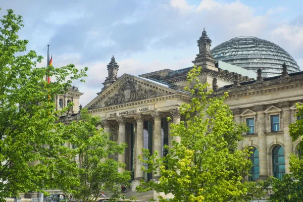 The Reichstag building, home of the German Bundestag, seen through green tree tops. 