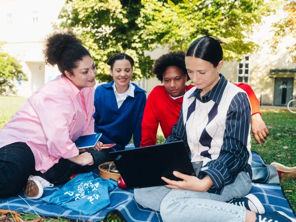 Circle U. Group of Students sitting in a park and looking at a laptop