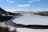 Snowy landscape with river in front and high mountains in the distance
